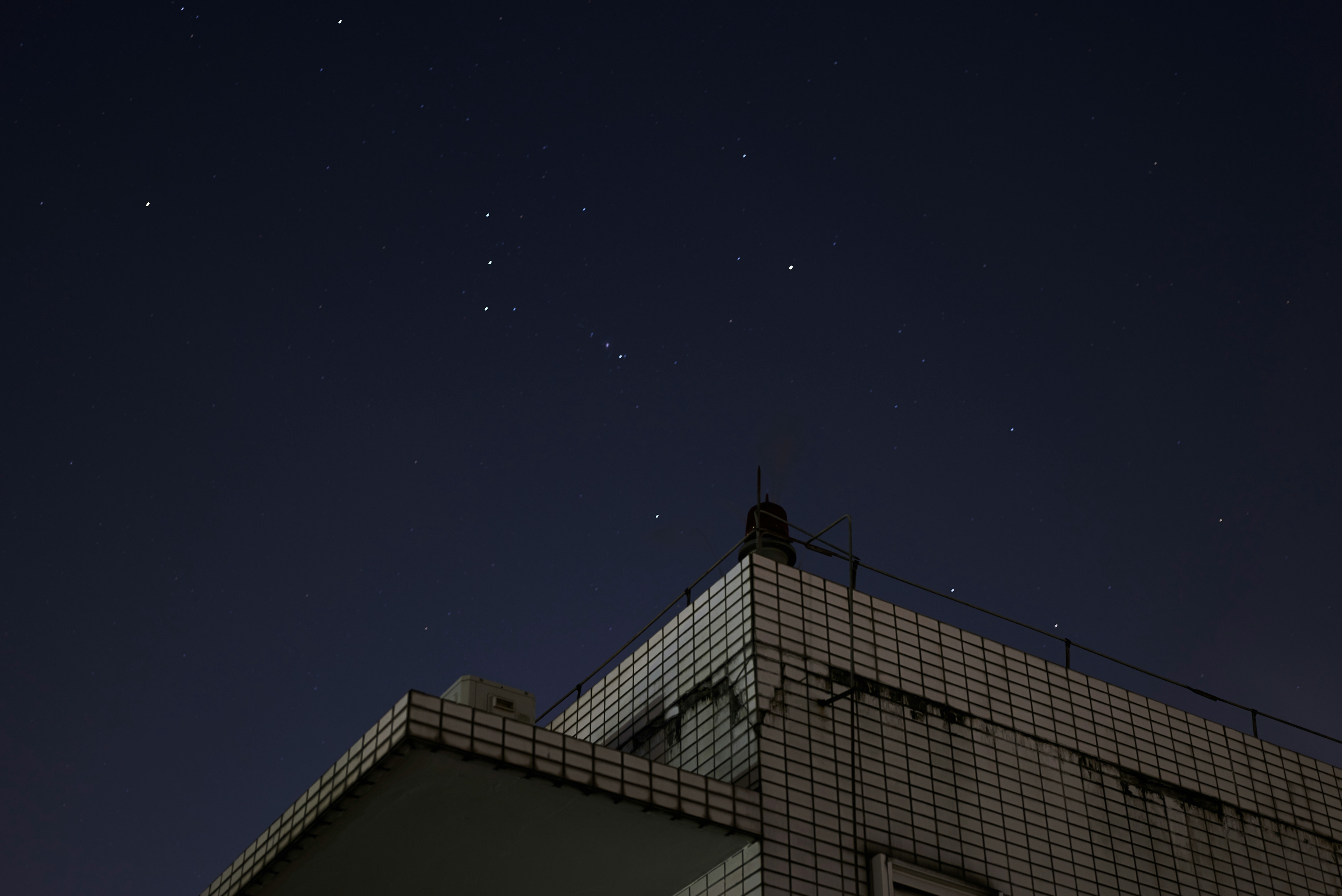 冬の夜空に広がる星々と、湯けむりが漂う温泉街を遠くから見渡す風景