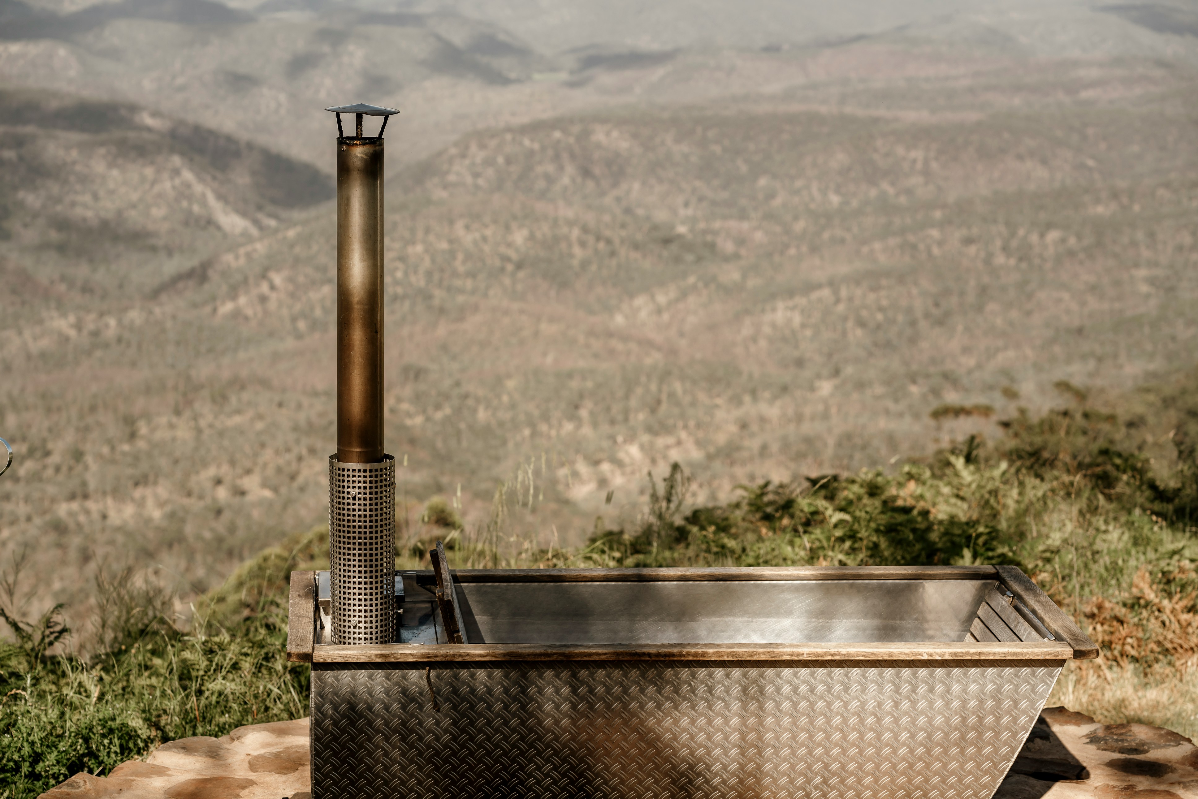 湯之峰温泉の「つぼ湯」を上から見下ろした風景と、川沿いに立ち上る湯けむり